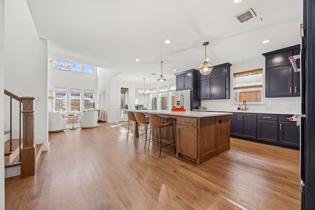 kitchen featuring decorative backsplash, light wood-type flooring, high end fridge, pendant lighting, and a kitchen island