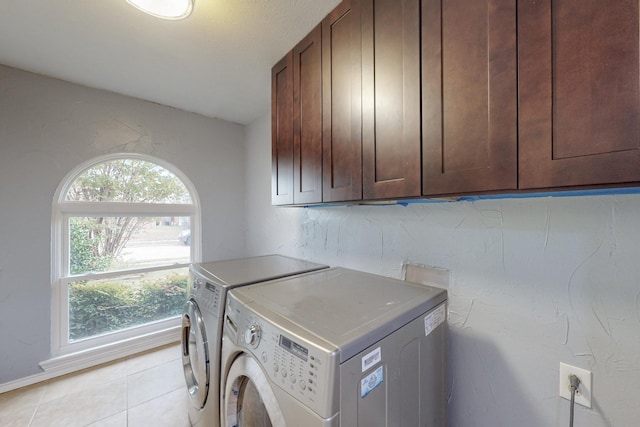 laundry area featuring cabinets, light tile patterned floors, and washing machine and clothes dryer