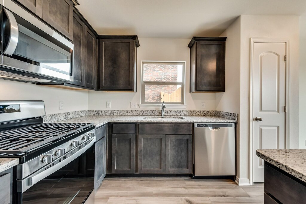 kitchen featuring sink, dark brown cabinetry, stainless steel appliances, and light hardwood / wood-style flooring