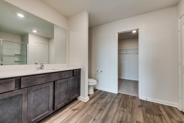 bathroom with hardwood / wood-style flooring, vanity, toilet, and an enclosed shower