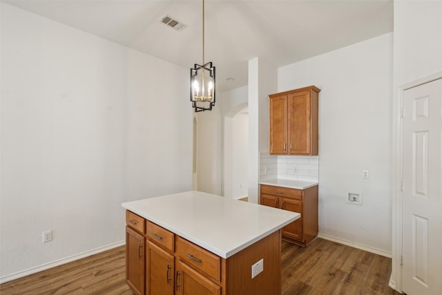 kitchen featuring backsplash, a center island, hanging light fixtures, and hardwood / wood-style flooring