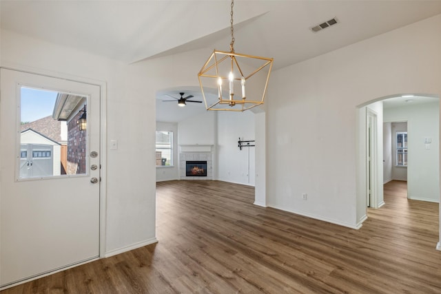 unfurnished living room with a fireplace, hardwood / wood-style floors, ceiling fan with notable chandelier, and lofted ceiling