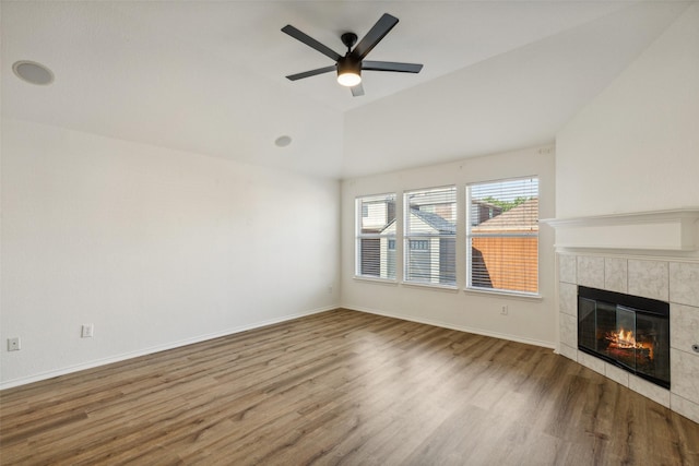 unfurnished living room featuring hardwood / wood-style flooring, ceiling fan, lofted ceiling, and a tiled fireplace