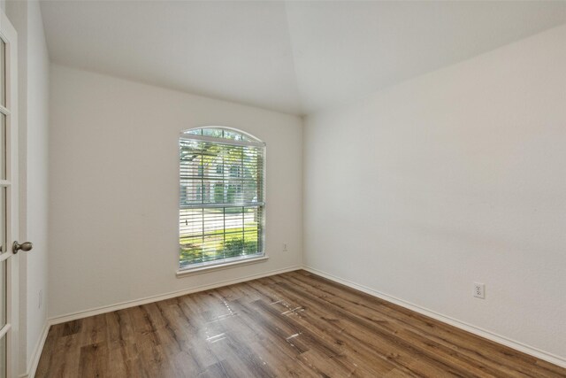 unfurnished room featuring vaulted ceiling and hardwood / wood-style flooring