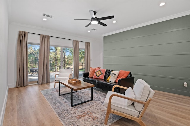 living room featuring ceiling fan, ornamental molding, and light hardwood / wood-style flooring