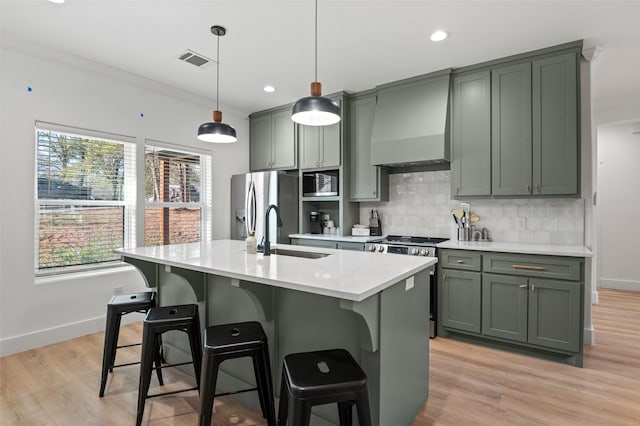 kitchen featuring custom exhaust hood, a kitchen island with sink, crown molding, sink, and stainless steel appliances