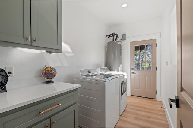 washroom featuring washer and dryer, cabinets, light hardwood / wood-style floors, and water heater