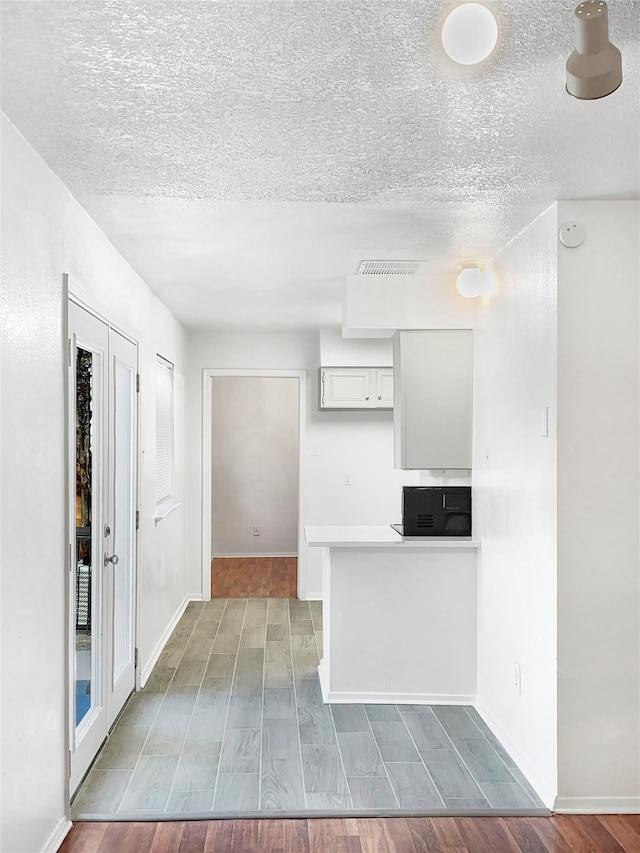 kitchen with hardwood / wood-style floors, white cabinetry, and a textured ceiling