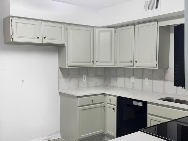 kitchen featuring decorative backsplash, black dishwasher, and light stone counters