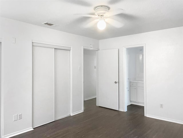 unfurnished bedroom featuring a closet, connected bathroom, dark hardwood / wood-style floors, and ceiling fan