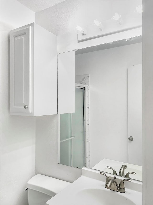 bathroom with vanity, walk in shower, a textured ceiling, and toilet