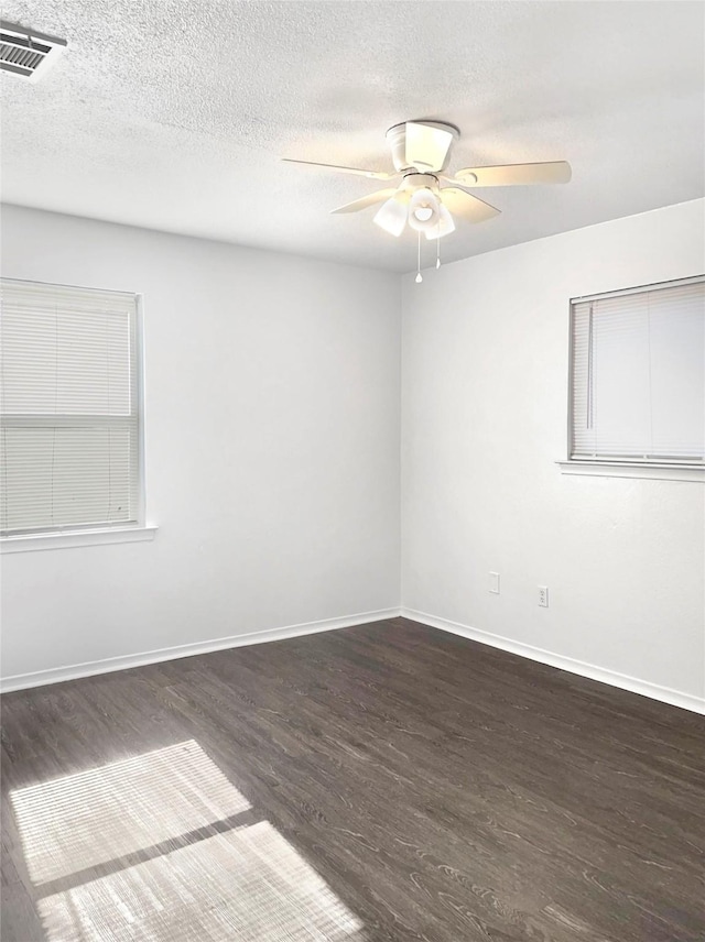 empty room with a textured ceiling, ceiling fan, and dark hardwood / wood-style floors