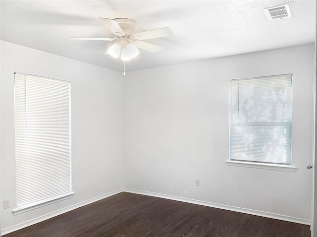 empty room with ceiling fan, dark wood-type flooring, and a textured ceiling