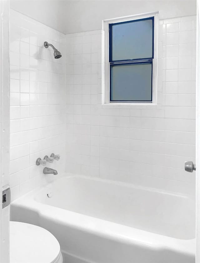 bathroom with toilet and tiled shower / bath combo