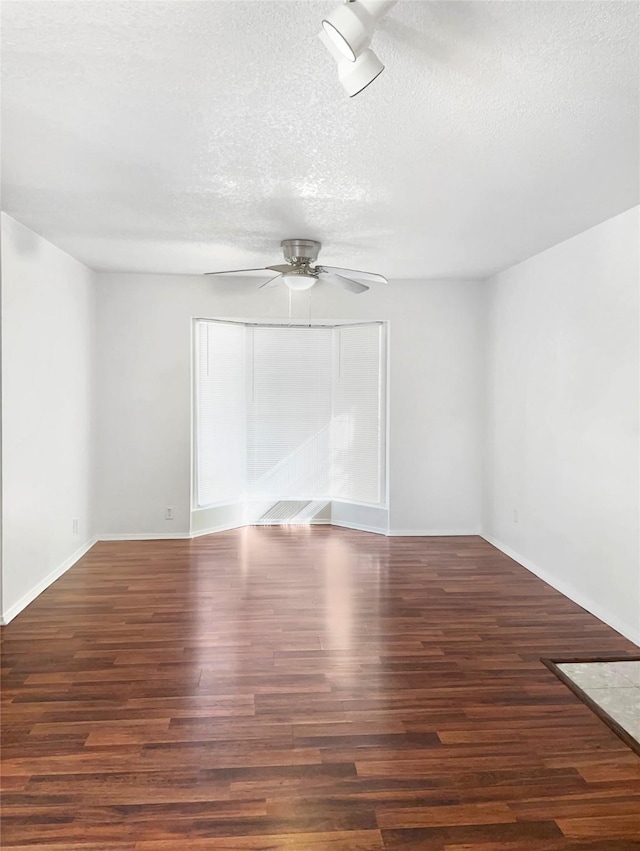 spare room featuring dark hardwood / wood-style floors, ceiling fan, and a textured ceiling