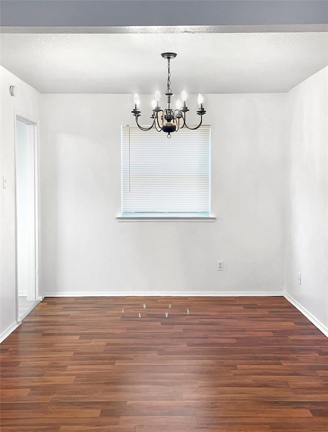 unfurnished dining area with a textured ceiling, a notable chandelier, and dark hardwood / wood-style flooring