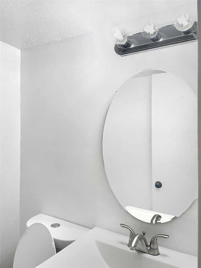 bathroom featuring sink, toilet, and a textured ceiling