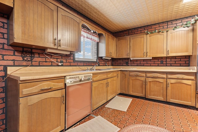 kitchen with dishwashing machine, sink, and brick wall