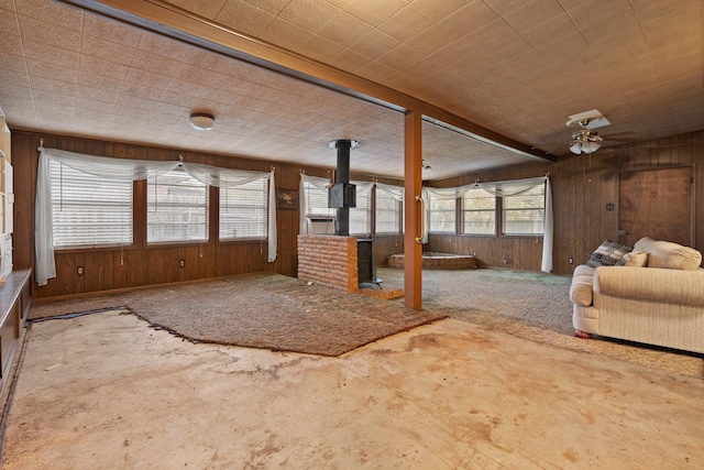 unfurnished living room with ceiling fan and wood walls