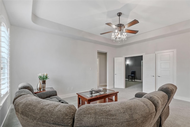 living room featuring a raised ceiling, light carpet, and ceiling fan