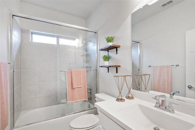 full bathroom featuring enclosed tub / shower combo, vanity, and toilet