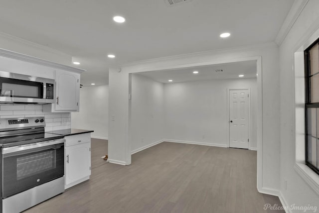 kitchen with white cabinets, light hardwood / wood-style flooring, ornamental molding, tasteful backsplash, and stainless steel appliances