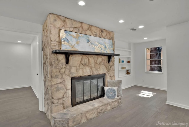 unfurnished living room featuring a stone fireplace and dark wood-type flooring