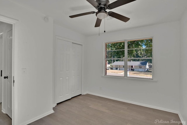 unfurnished bedroom with ceiling fan, light hardwood / wood-style floors, a closet, and multiple windows