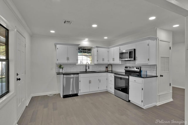 kitchen with white cabinets, crown molding, sink, light wood-type flooring, and stainless steel appliances