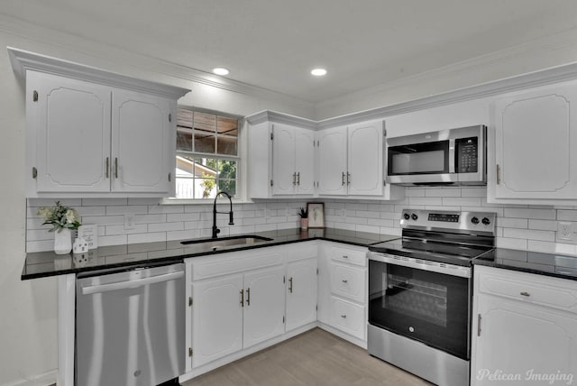 kitchen featuring sink, light hardwood / wood-style flooring, ornamental molding, appliances with stainless steel finishes, and white cabinetry