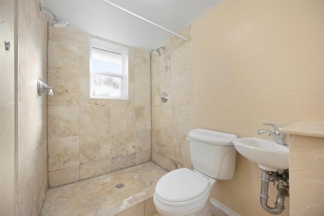 bathroom with a tile shower and toilet