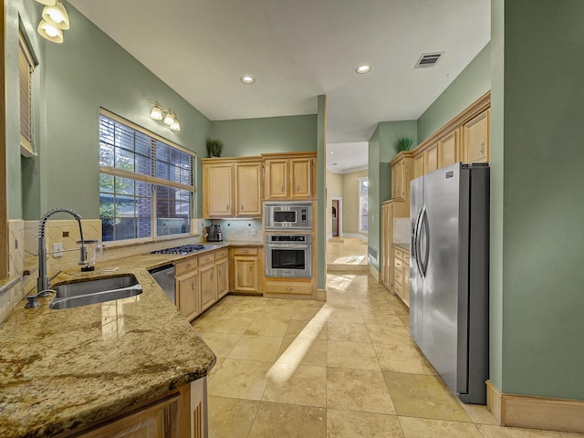 kitchen featuring light stone countertops, sink, stainless steel appliances, tasteful backsplash, and light brown cabinetry