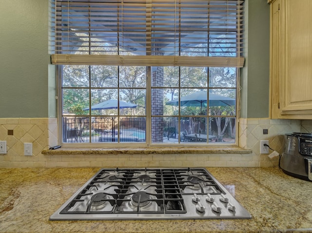 kitchen with stainless steel gas stovetop, a healthy amount of sunlight, and decorative backsplash