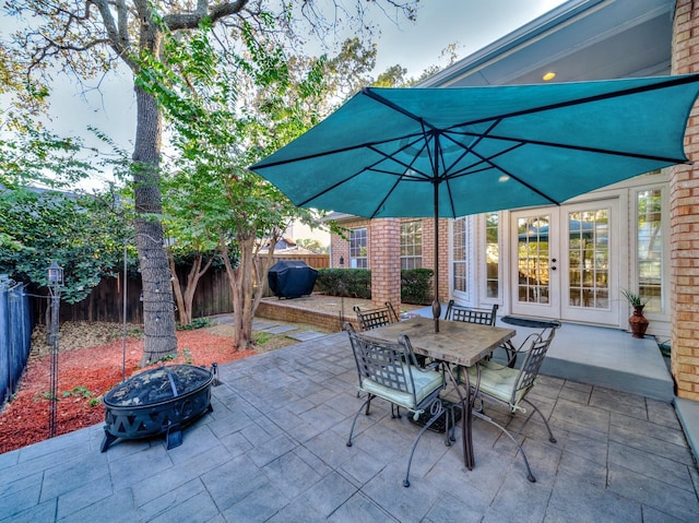 view of patio / terrace with a fire pit, a grill, and french doors