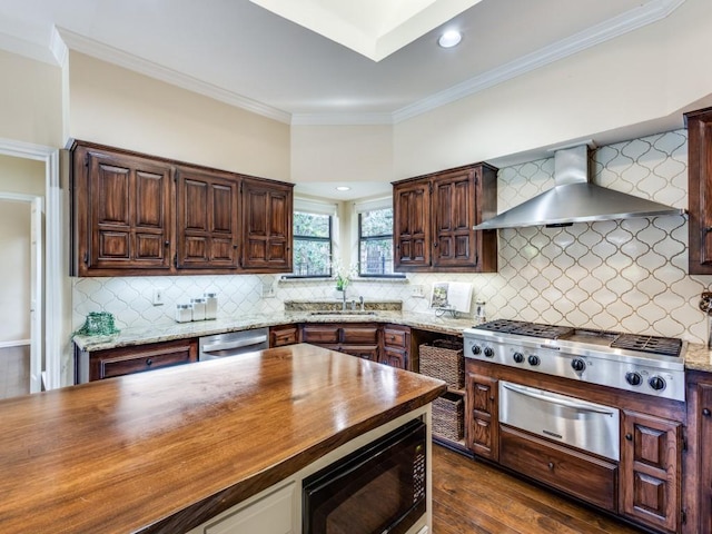 kitchen with wall chimney exhaust hood, dark wood-type flooring, stainless steel appliances, butcher block countertops, and decorative backsplash