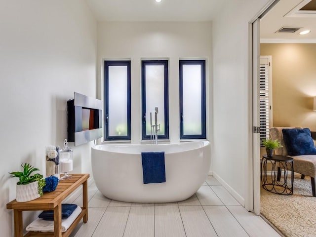 bathroom featuring tile patterned floors, crown molding, and a tub to relax in