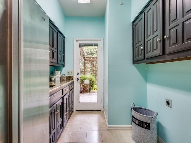 washroom featuring hookup for an electric dryer, light tile patterned flooring, and cabinets