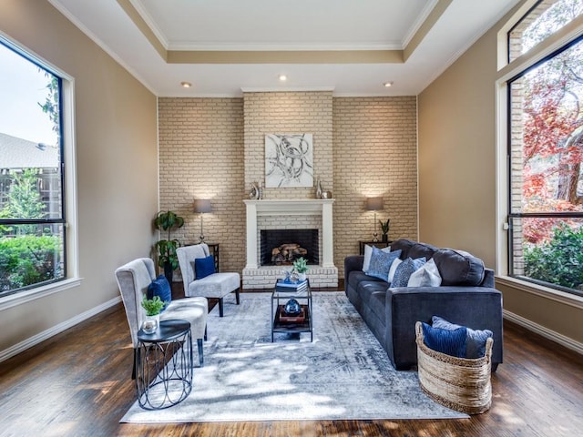 living room with dark hardwood / wood-style floors, crown molding, and a brick fireplace