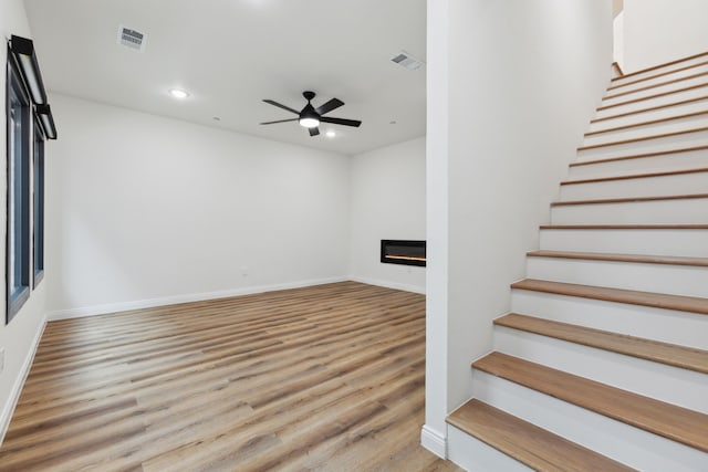 stairs with hardwood / wood-style flooring and ceiling fan