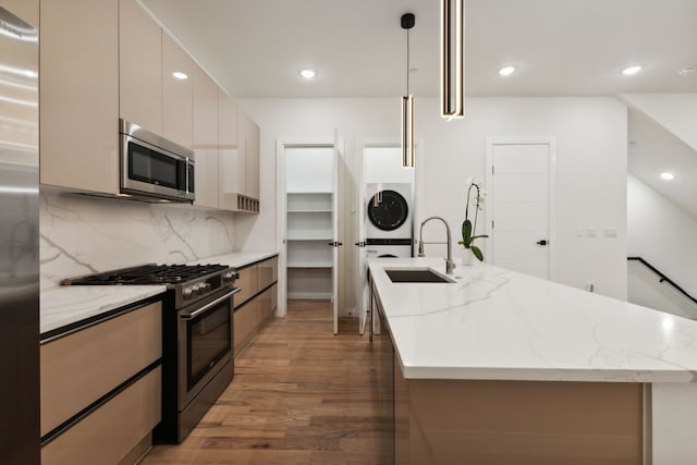 kitchen featuring decorative light fixtures, stainless steel appliances, light stone countertops, and sink