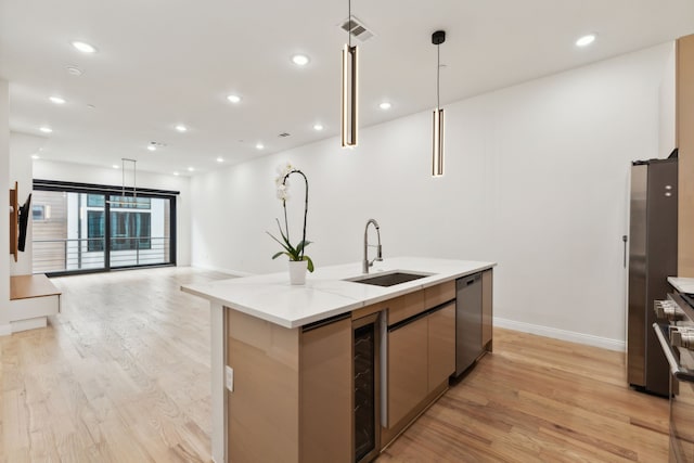 kitchen featuring decorative light fixtures, stainless steel appliances, a center island with sink, wine cooler, and sink