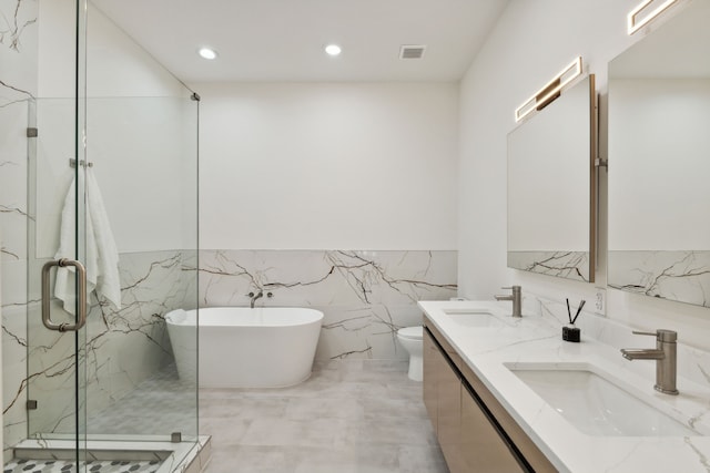 full bathroom featuring shower with separate bathtub, vanity, and toilet