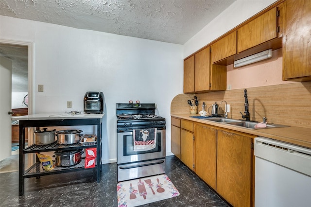 kitchen with stainless steel range with gas cooktop, tasteful backsplash, dishwasher, sink, and a textured ceiling