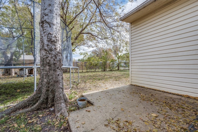 view of yard with a trampoline and a patio area