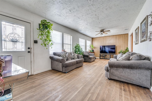 living room with ceiling fan, light hardwood / wood-style floors, and a textured ceiling