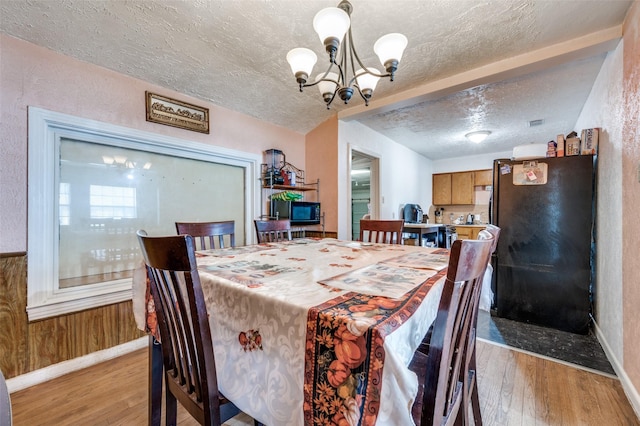 dining space featuring a textured ceiling, light hardwood / wood-style flooring, and a notable chandelier