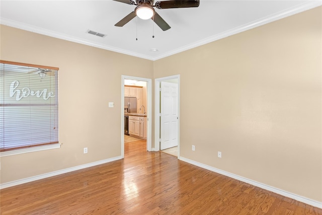 empty room with hardwood / wood-style floors, crown molding, ceiling fan, and a healthy amount of sunlight