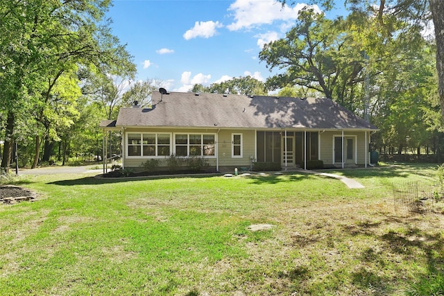 rear view of house featuring a sunroom and a lawn