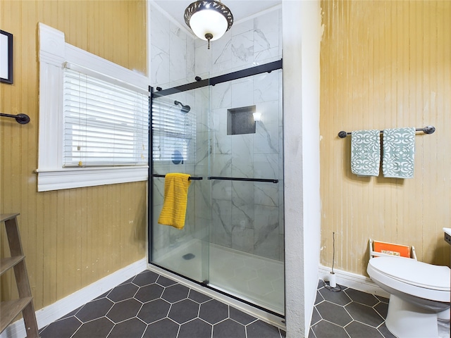 bathroom featuring tile patterned floors, wood walls, toilet, and walk in shower