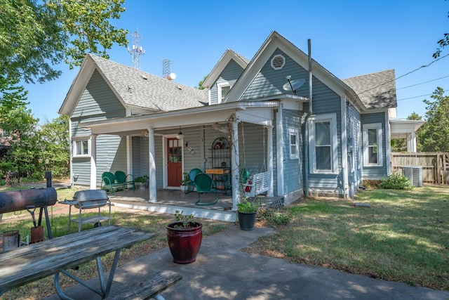 rear view of house with covered porch, a yard, and central AC unit